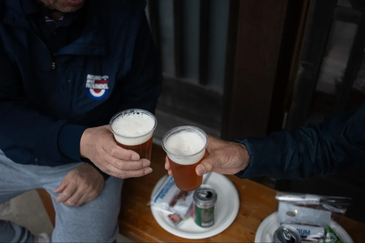 写真：ベンチに座ってビールを乾杯している様子