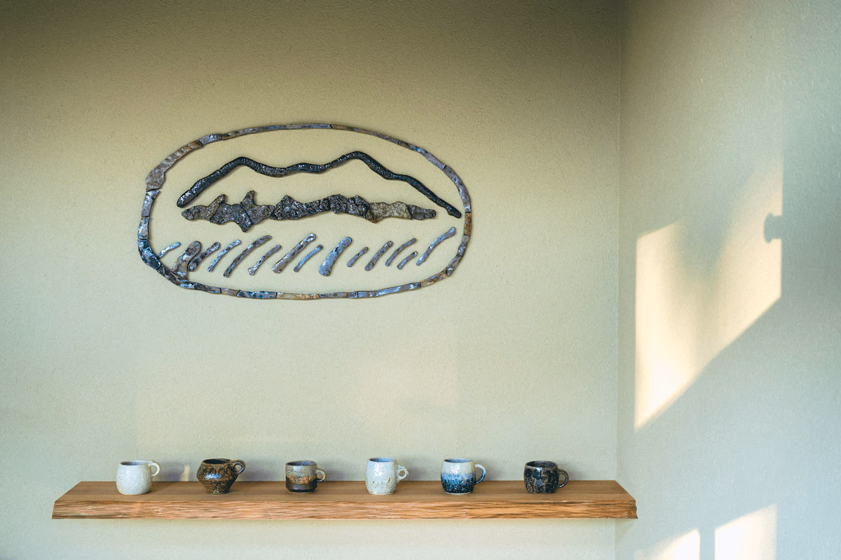 Ceramic logo mark and mugs lined up on a shelf