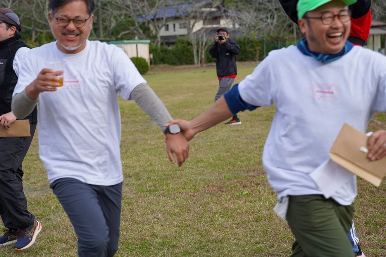 A man smiling and pulling another man's hand